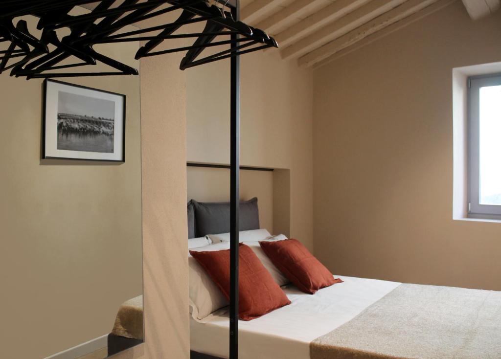 1 dormitorio con cama negra con dosel y almohadas de color naranja en Casa Monteme, en Montemerano