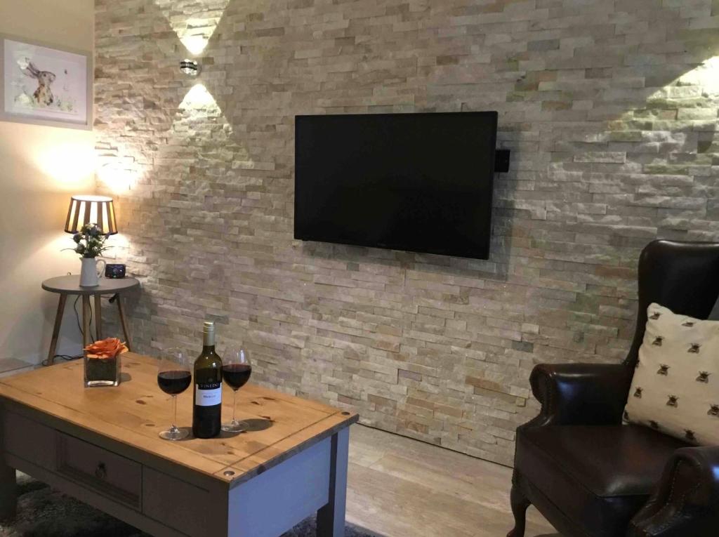 a living room with a tv on a brick wall at Plas Bach in Haverfordwest