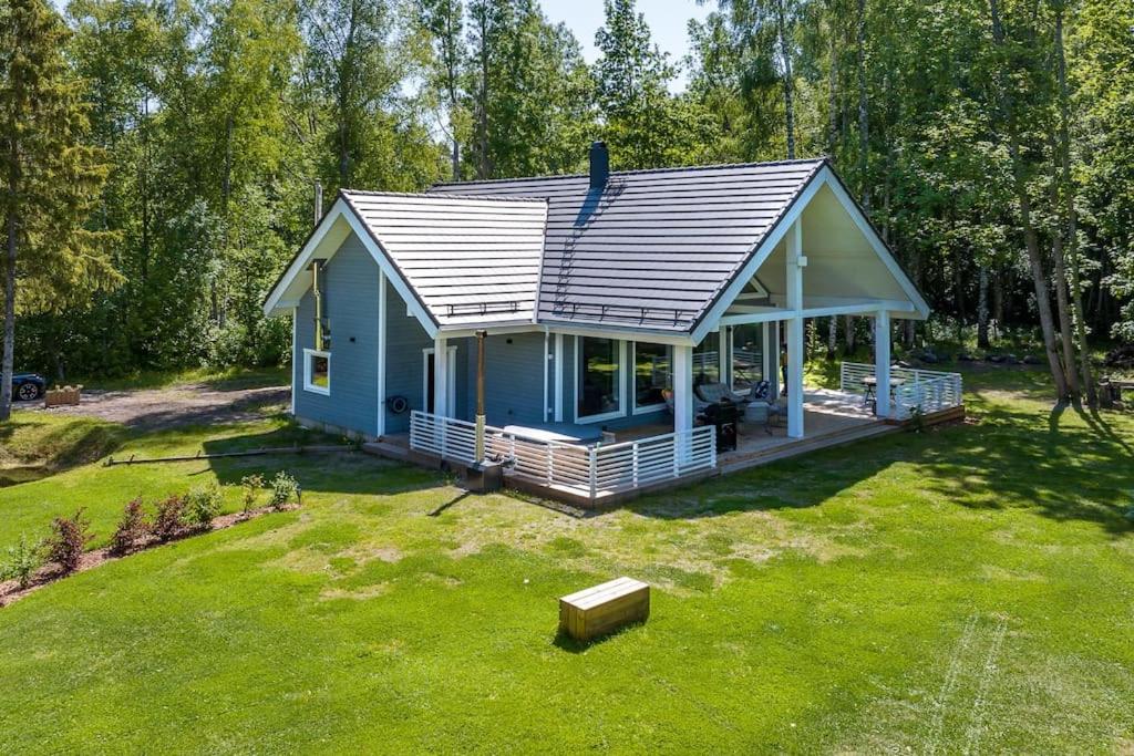 een klein blauw huis op een grasveld bij Modern villa with sauna & hot tub in Hiiumaa