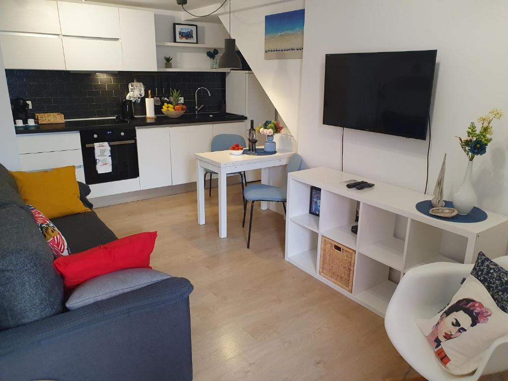 uma sala de estar com um sofá azul e uma cozinha em Korado Studio Apartment em Vrsar