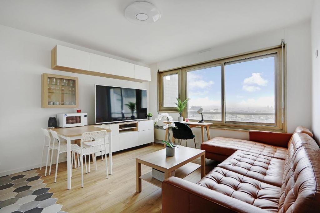 ein Wohnzimmer mit einem Sofa und einem Tisch sowie eine Küche in der Unterkunft Pick A Flat's Apartment in Montparnasse - Rue Vercingétorix in Paris
