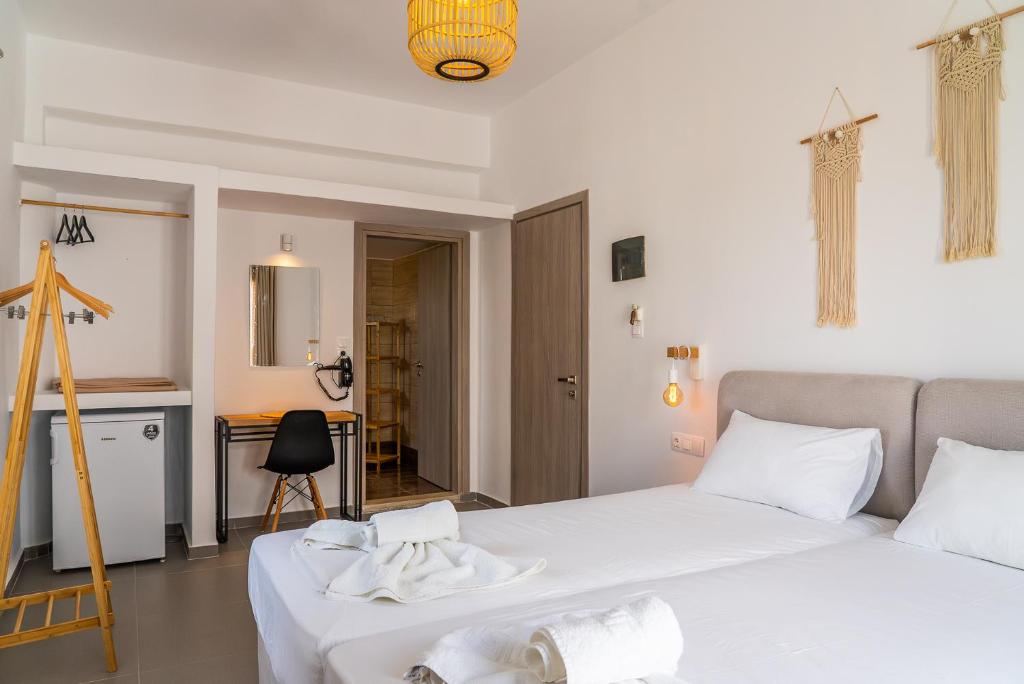 a bedroom with two beds with white sheets and a kitchen at Eleftheria Studios in Antiparos