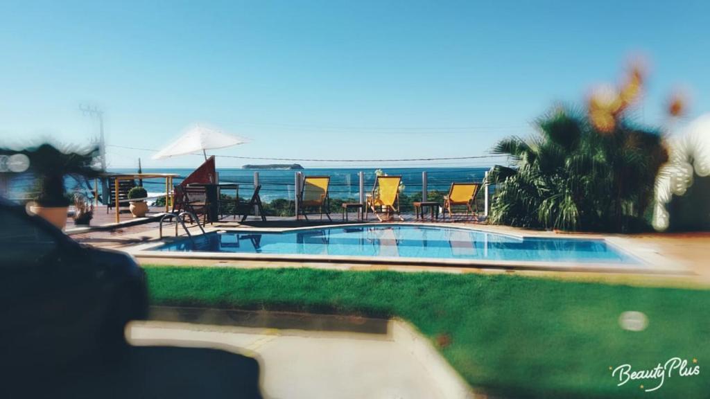 uma piscina com cadeiras e o oceano ao fundo em Pousada Bangalôs Da Mole - Florianópolis em Florianópolis