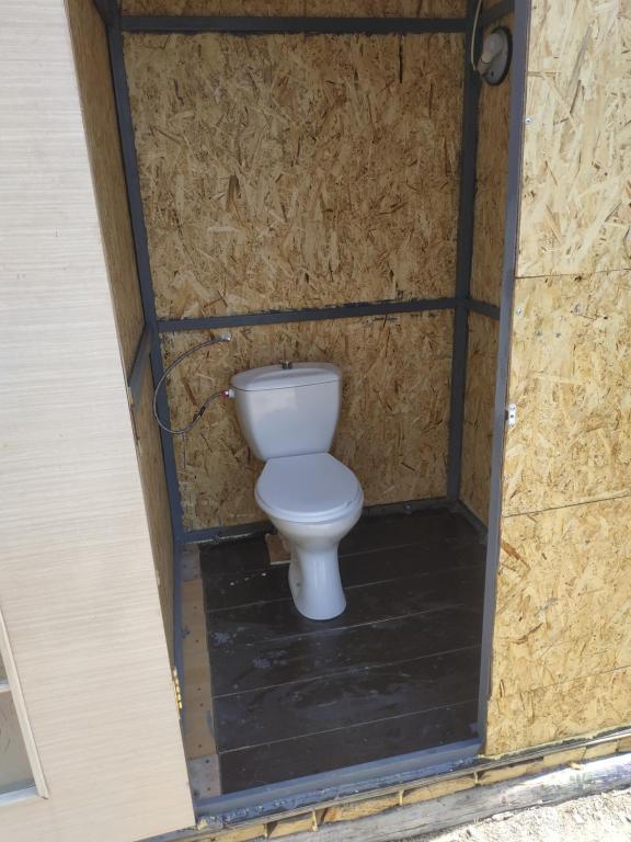 ein weißes WC in einem Zimmer mit einer Wand in der Unterkunft Дача посуточно Балхаш in Balqasch