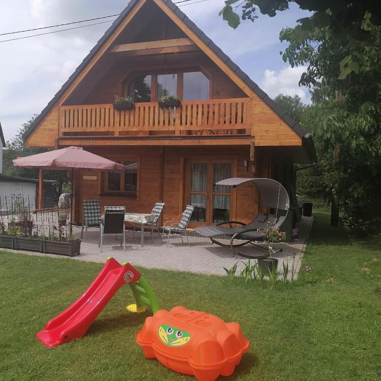 a wooden house with a playground in the yard at Blockbohlenhaus-Steiner-Lodge in Steinen