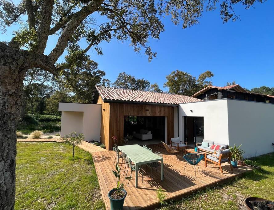 une cour arrière avec une terrasse en bois avec une table et des chaises dans l'établissement La villa d’Hortense, à Labenne