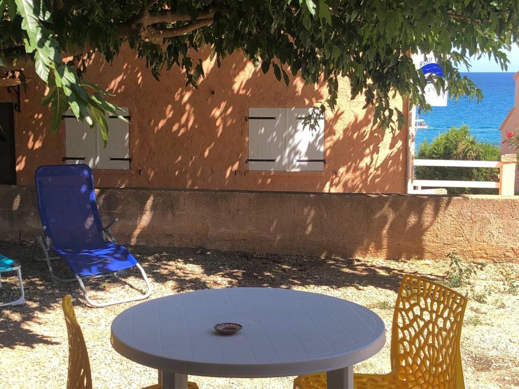 a table and chairs in front of a building with the ocean at Jolie T2 bord de mer corse du sud in Conca