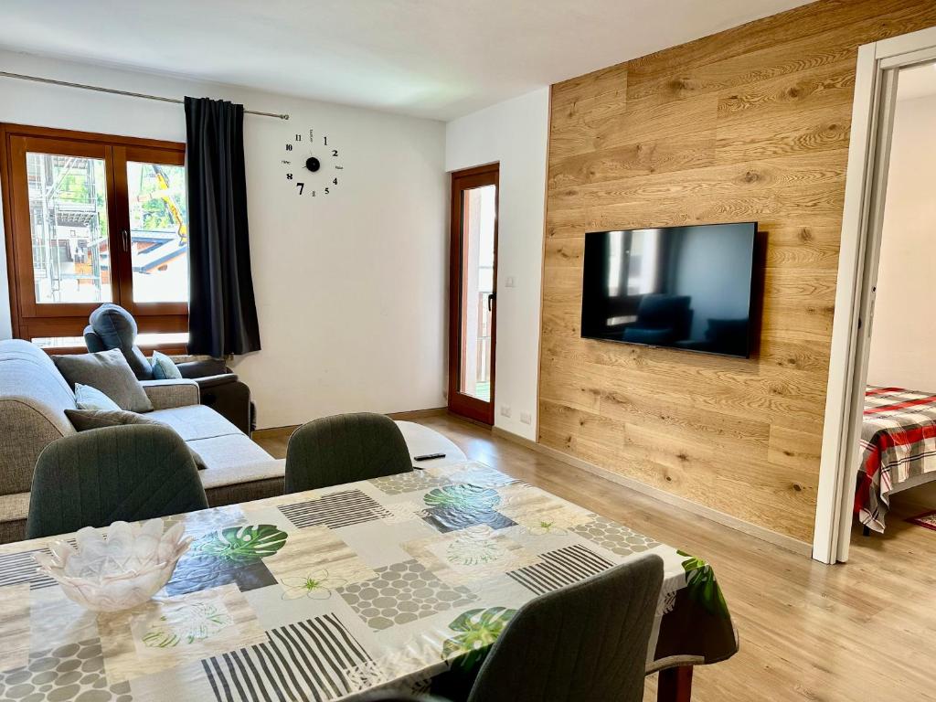 a living room with a table and a television on a wall at D'Hérens apartment in Breuil-Cervinia