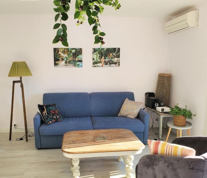 a living room with a blue couch and a table at Lou beach home 75 m2 à 300 m de la plage avec vue mer in La Ciotat