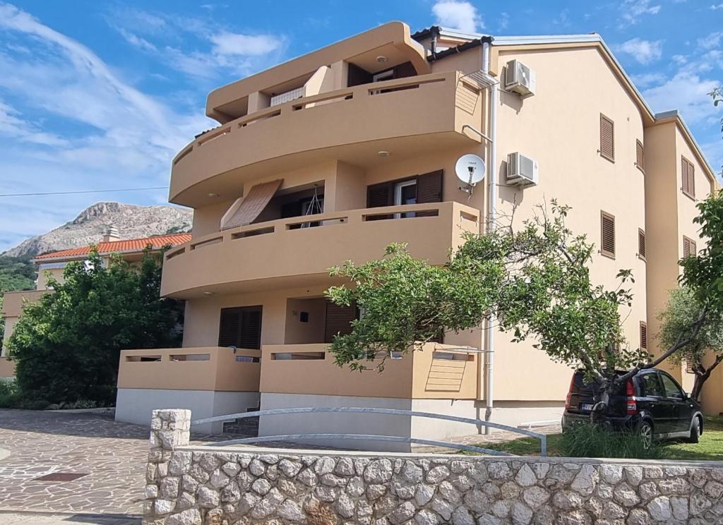 a building with a car parked in front of it at Apartments Barbalic D in Baška