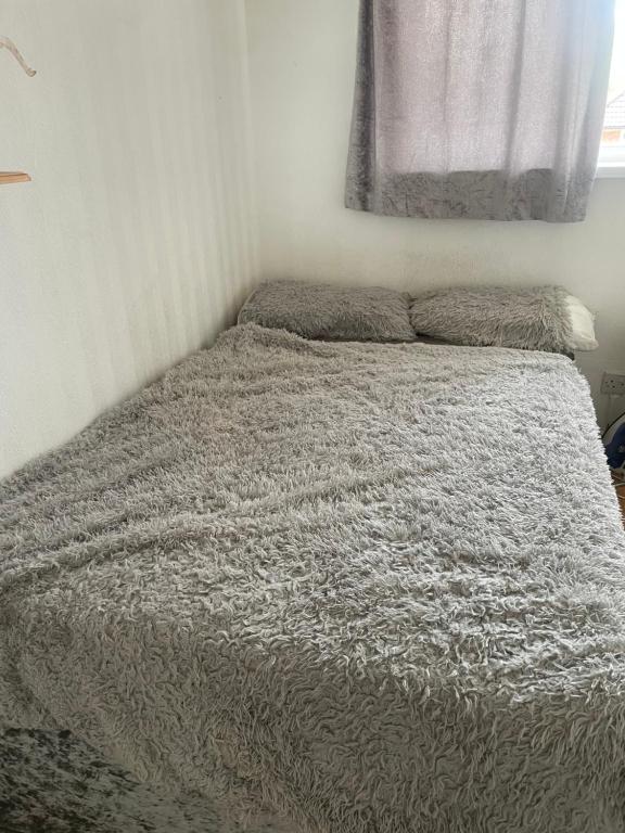 a bed with a gray comforter in a bedroom at Ultimate Cozy Room in Kirkstall