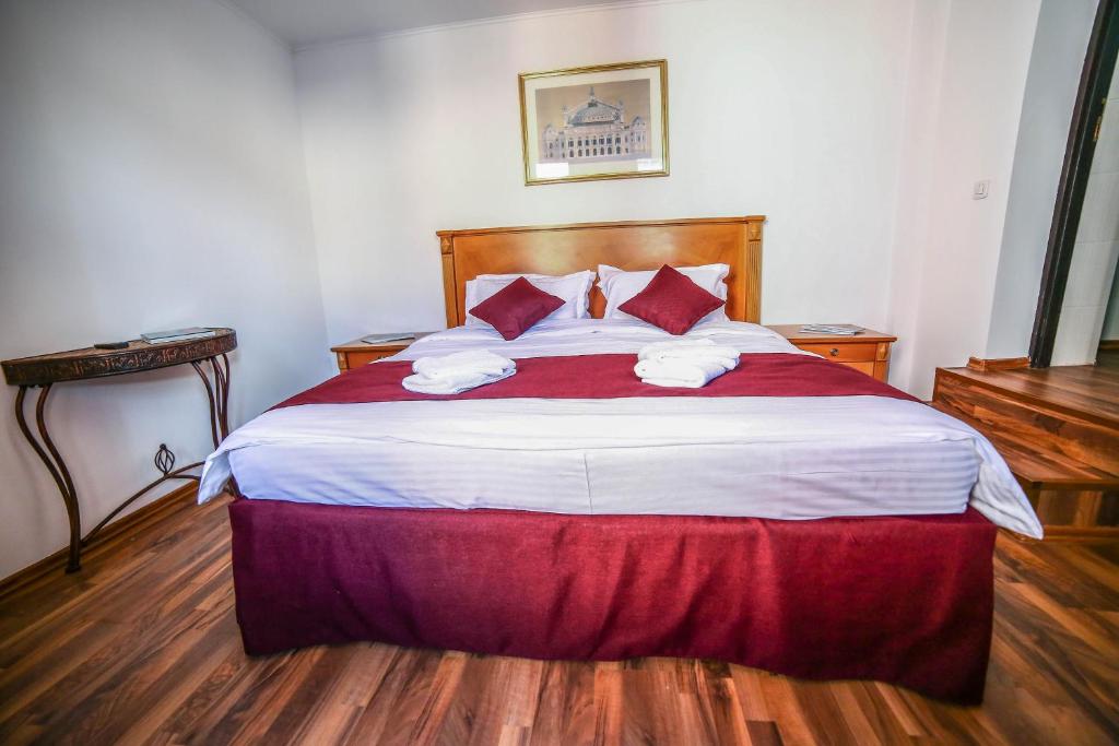 a bedroom with a large bed with red and white sheets at Bliss Residence in Bucharest