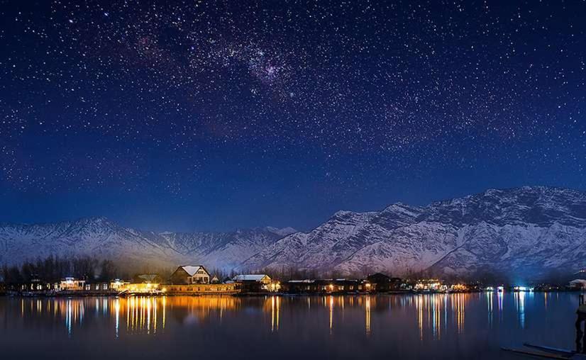 a starry night over a lake with mountains in the background at Gulshan Group of HouseBoat in Srinagar