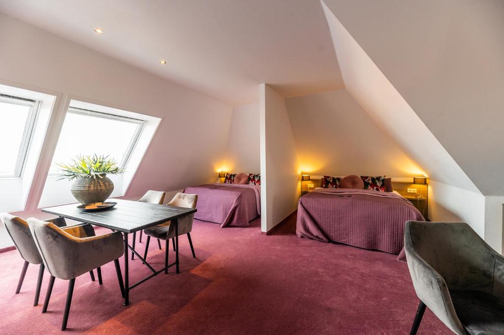 a attic room with two beds and a table and chairs at Hotel Bru in Bruinisse