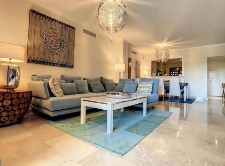 ein Wohnzimmer mit einem Sofa und einem Tisch in der Unterkunft Appartement luxueux, piscine, padel et golf de Doña Julia in Bahia de Casares