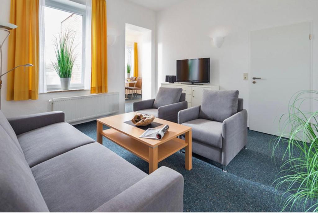 ein Wohnzimmer mit einem Sofa, 2 Stühlen und einem Tisch in der Unterkunft Villa Rosenhof in Norderney