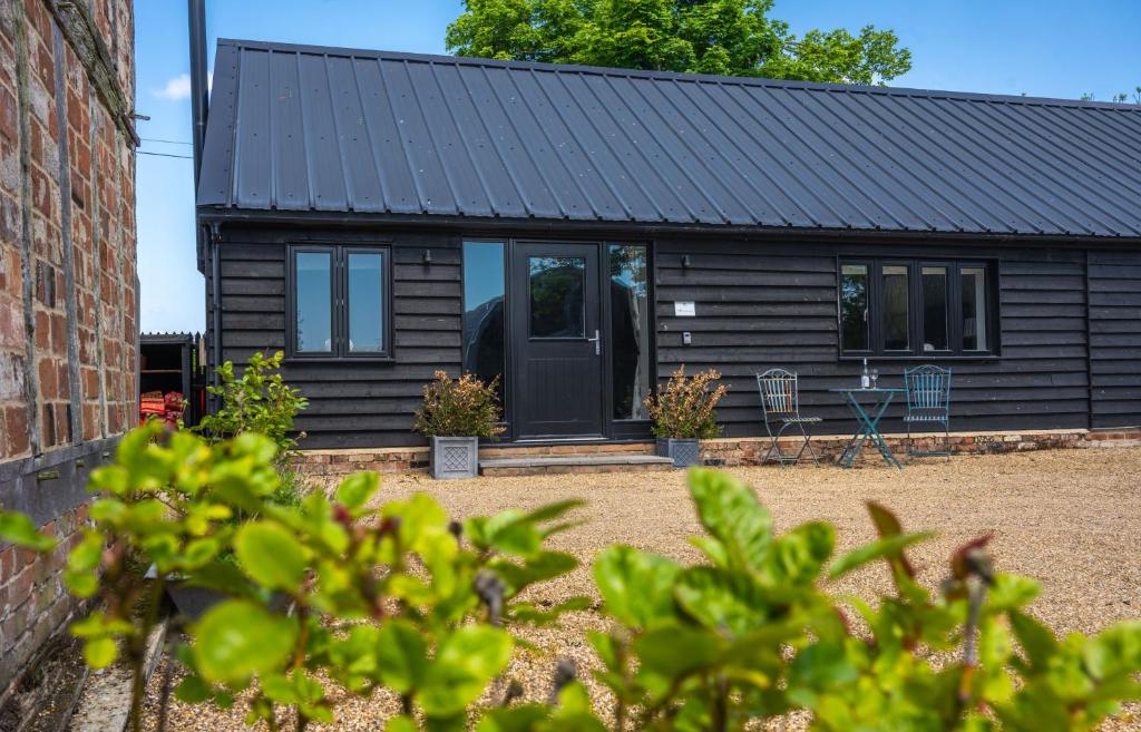 une maison noire avec un toit noir dans l'établissement The Cowshed at Green Valley Farm, à Laxfield