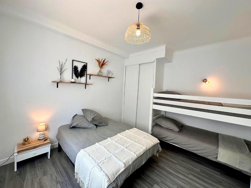 a white bedroom with a bed and a night stand at Paradis - Hyper Centre, a deux pas de la Mer ! in Canet-en-Roussillon