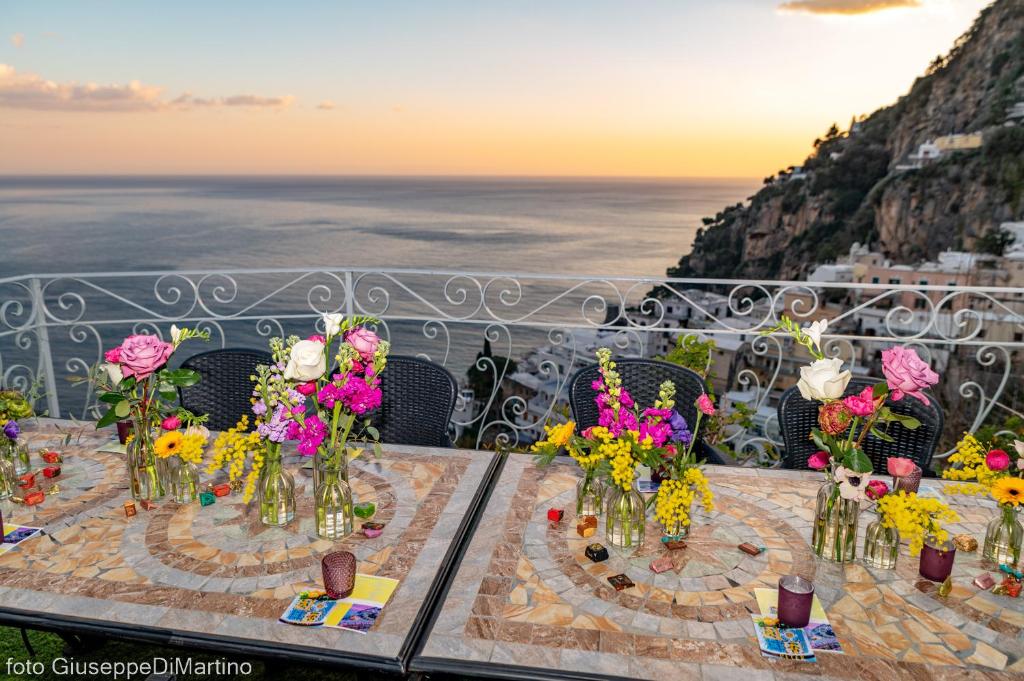 una mesa con flores en jarrones en el balcón en Maristella, en Positano