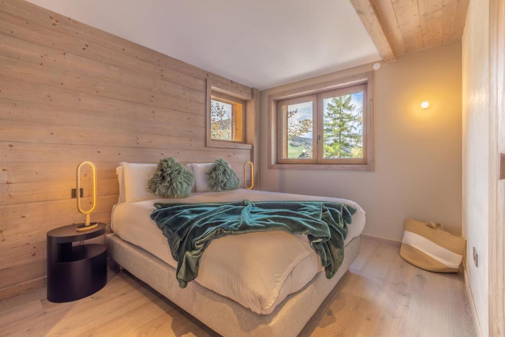 a bedroom with a bed with a wooden wall at Bleu Eskape - Appartement in Megève