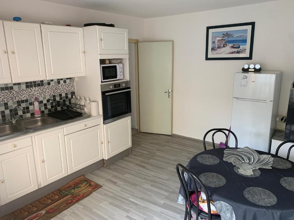 uma cozinha com armários brancos, uma mesa e um frigorífico em Le Retro em Le May-sur-Èvre