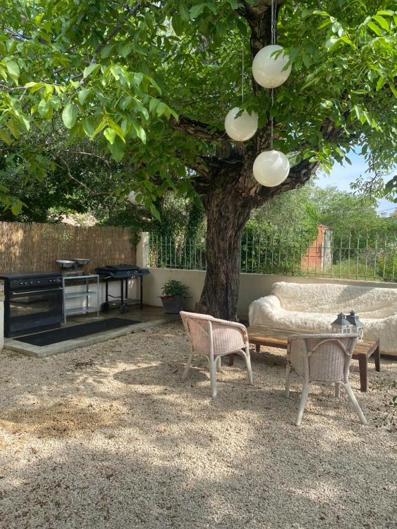 une table et des chaises assises sous un arbre dans l'établissement Mas des garrigues, à Bouchet