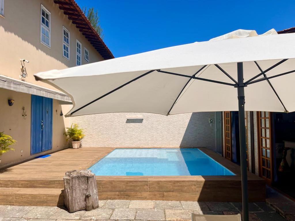 um grande guarda-chuva branco ao lado de uma piscina em Quarto c/ Banheiro próximo a Praia da Barra da Tijuca no Rio de Janeiro