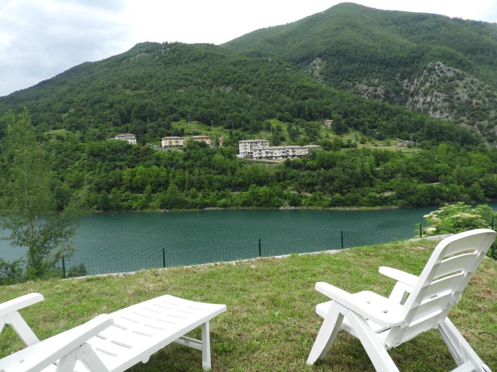 duas cadeiras brancas sentadas numa colina ao lado de um lago em Casa Vacanze Giovanna em Vagli di Sotto