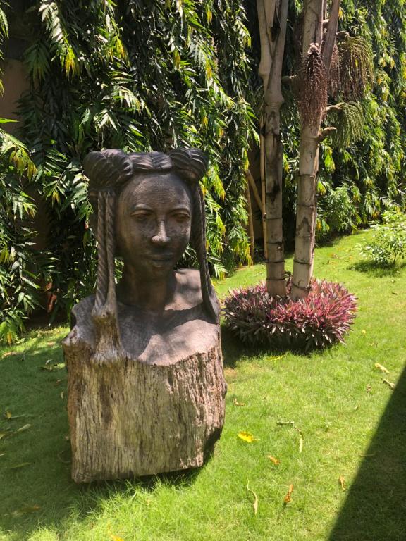 una estatua de una mujer sentada en un tronco de árbol en Nomads en Lomé