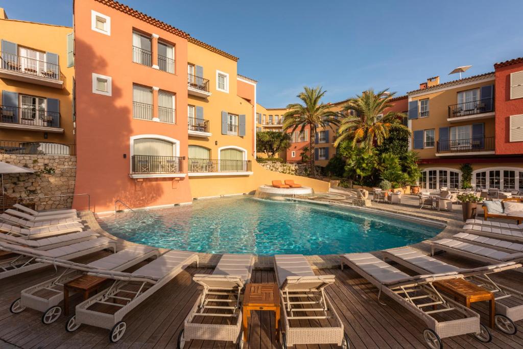 een zwembad met ligstoelen en een gebouw bij Hotel Byblos Saint-Tropez in Saint-Tropez