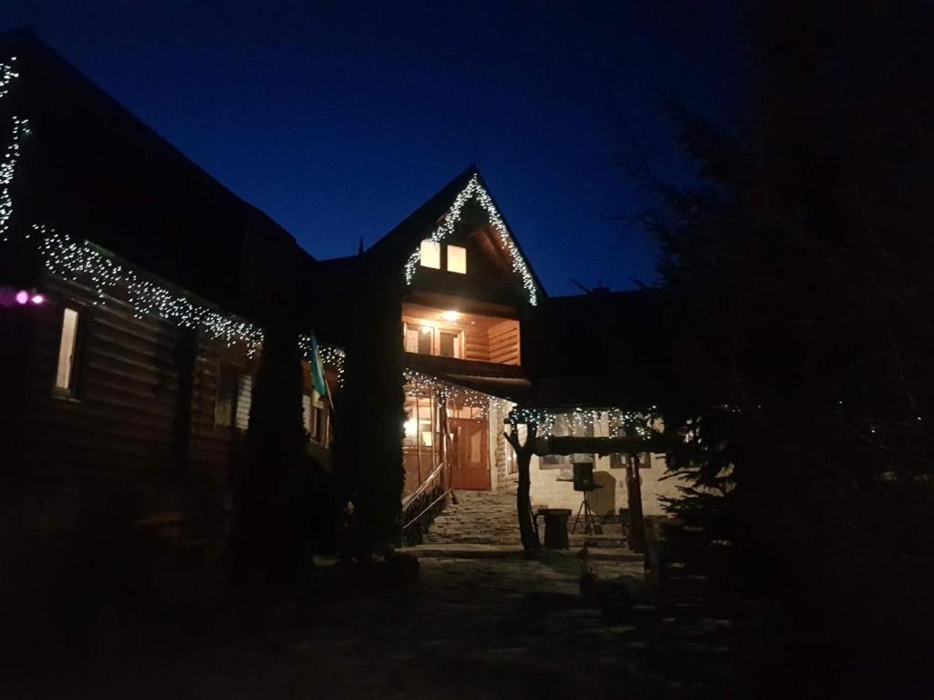 ein nachts beleuchtetes Haus mit Weihnachtsbeleuchtung in der Unterkunft Muzey-sadyba Grazhda in Bukowel