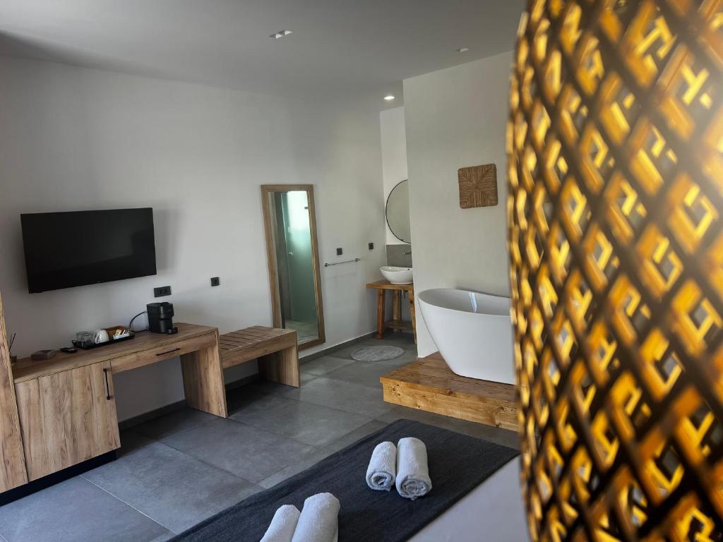 a room with a tub and a tv and a bathroom at Sydney Hotel in Kefalos