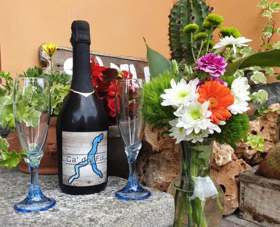 a bottle of wine and two wine glasses and flowers at Cà del Fili in Lenno