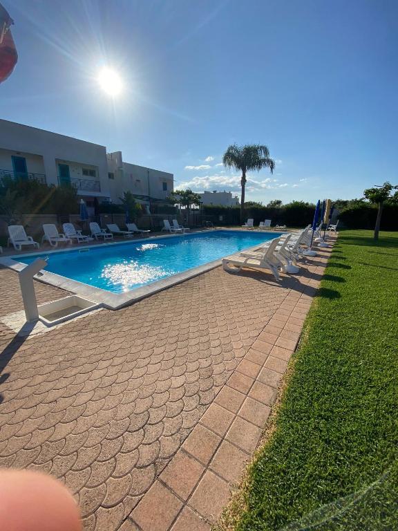 a swimming pool with lounge chairs next to a building at Appartamento MaRi con piscina in Torre Lapillo
