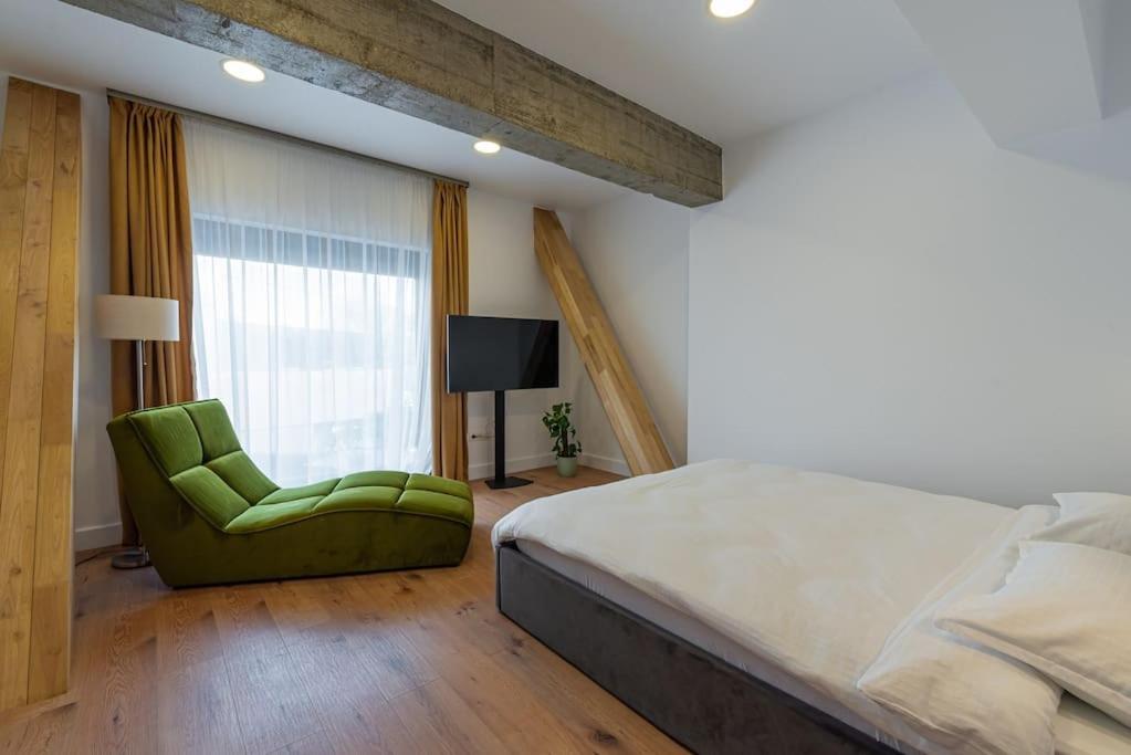 1 dormitorio con 1 cama y 1 silla verde en Fabrica Apartments 14 en Cluj-Napoca