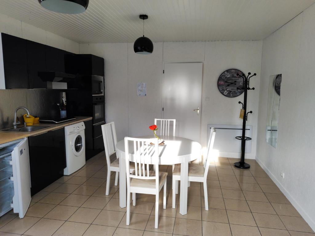 cocina con mesa blanca y sillas blancas en Chalet 38 m2, au calme reposant, près du puy /fou, en Saint-Pierre-des-Échaubrognes
