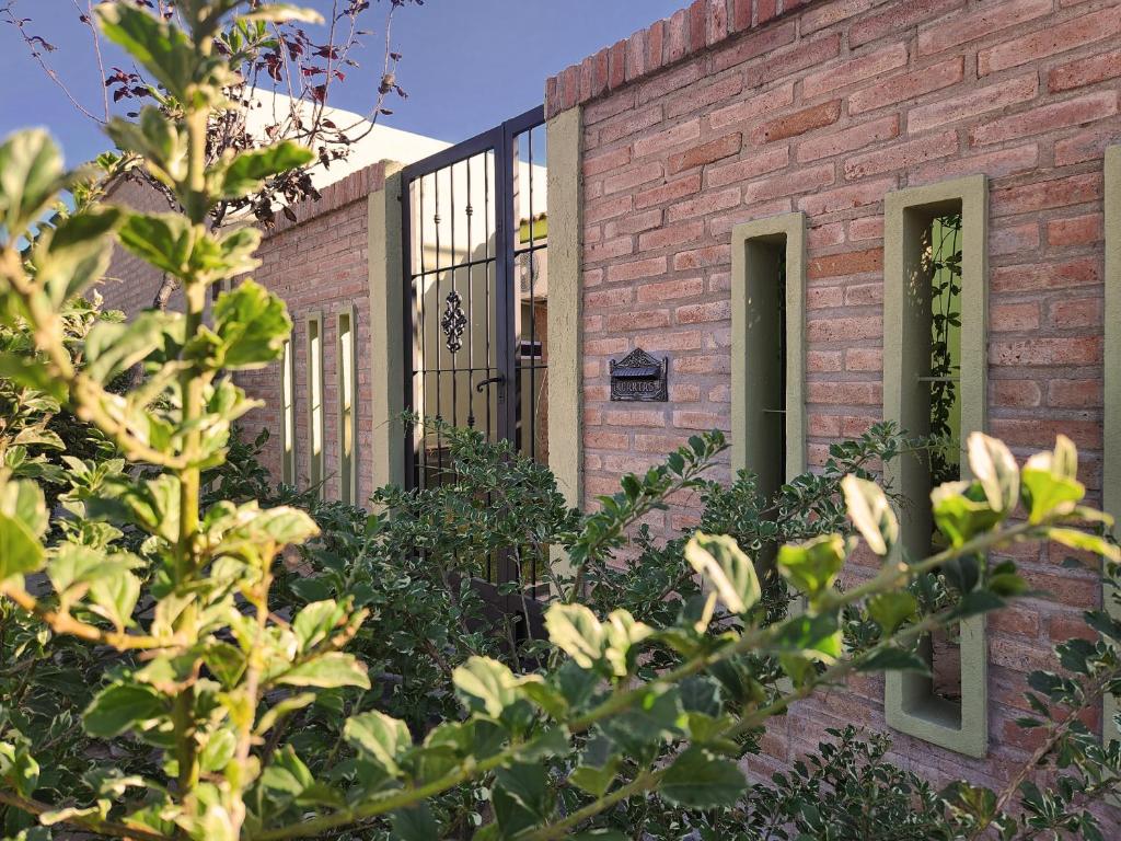 un edificio de ladrillo con una puerta negra y arbustos en Casa Mandarina en La Punta