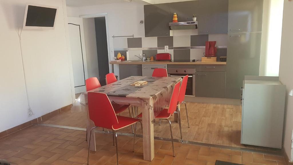 a kitchen with a wooden table and red chairs at Au rayon de soleil in Trédias