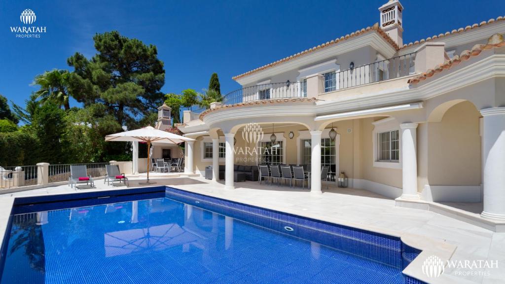 una casa grande con piscina frente a ella en Villa Susana, en Quinta do Lago