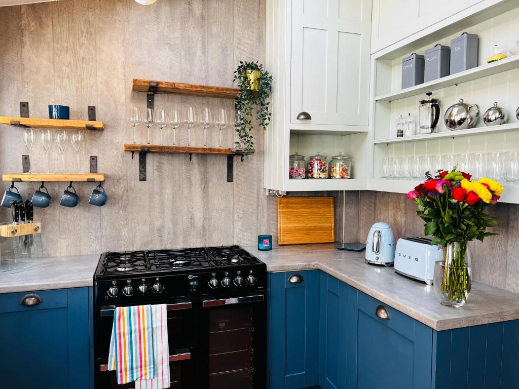 a kitchen with blue cabinets and a stove top oven at Nightingale Cottage in Llantwit Major