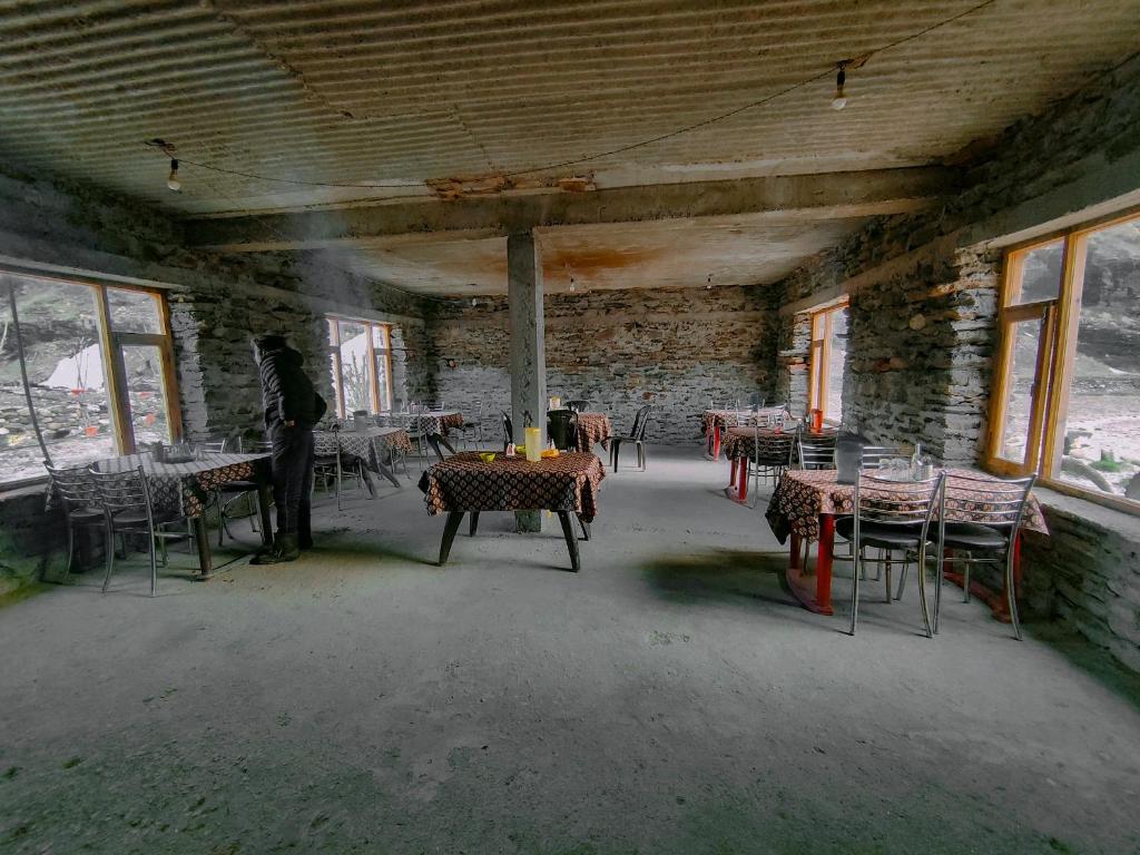una habitación vacía con mesas y sillas en un edificio en Sangam River camp en Sissu