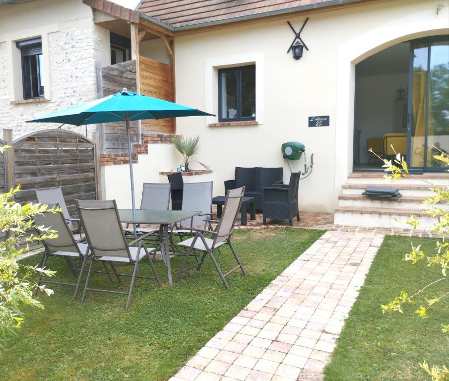 patio con tavolo, sedie e ombrellone di L'Abaca 23 a Sainte-Geneviève-lès-Gasny