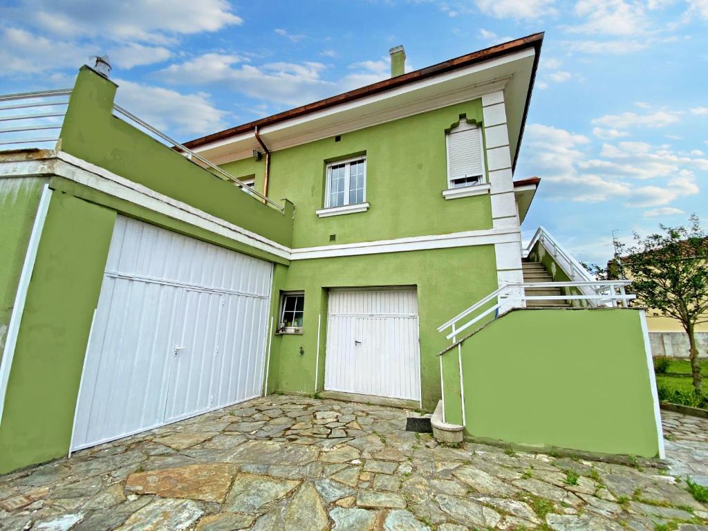 a green house with two garage doors and a stone driveway at Casa Elsa in Torrelavega