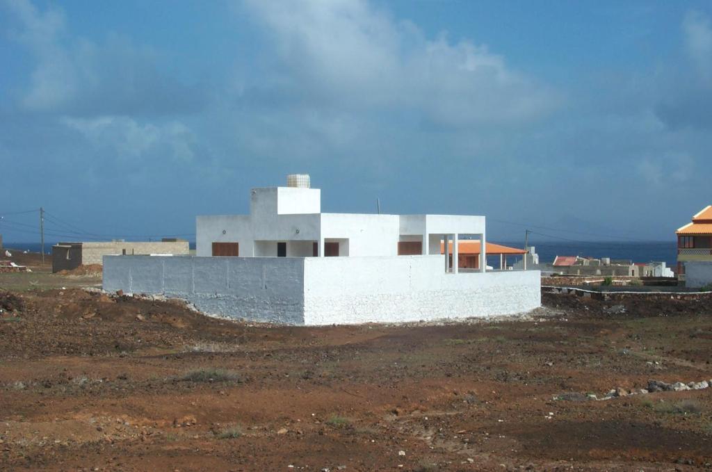 a white building on a hill in a field at Beach Villa with pool in Mindelo