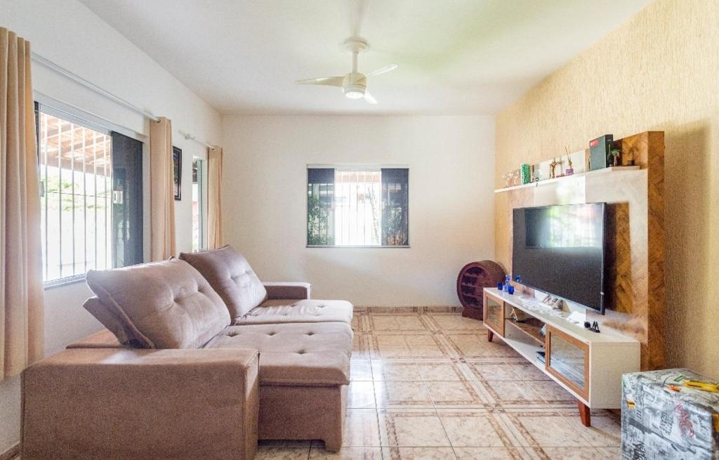 uma sala de estar com um sofá e uma televisão de ecrã plano em Casa aconchegante à 200m da praia em Rio das Ostras