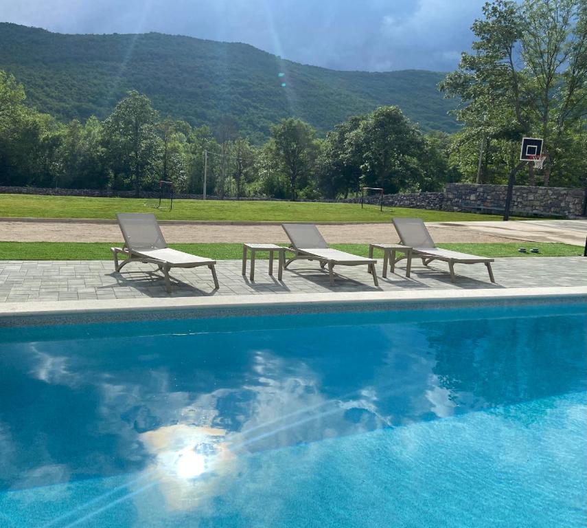 zwei Stühle und ein Pool mit Bergen im Hintergrund in der Unterkunft VIlla Luka - new isolated villa with heated pool, jacuzi and sauna in Gračac