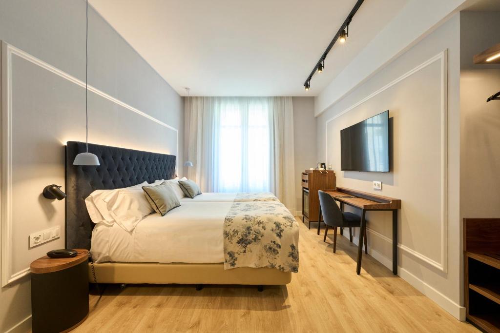 a bedroom with a bed and a desk and a television at Catalonia El Pilar in Zaragoza