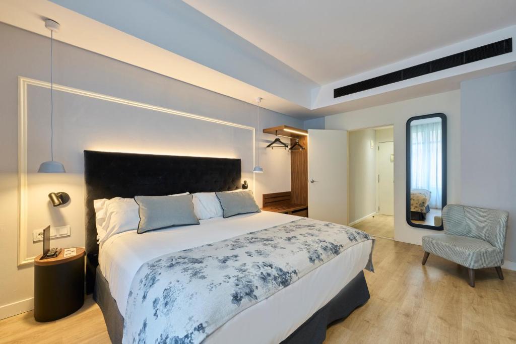 a bedroom with a large bed and a chair at Catalonia El Pilar in Zaragoza