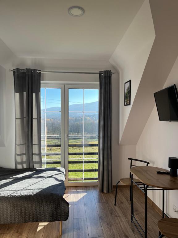 a bedroom with a bed and a table and a window at Agroturystyka Liana in Polanica-Zdrój