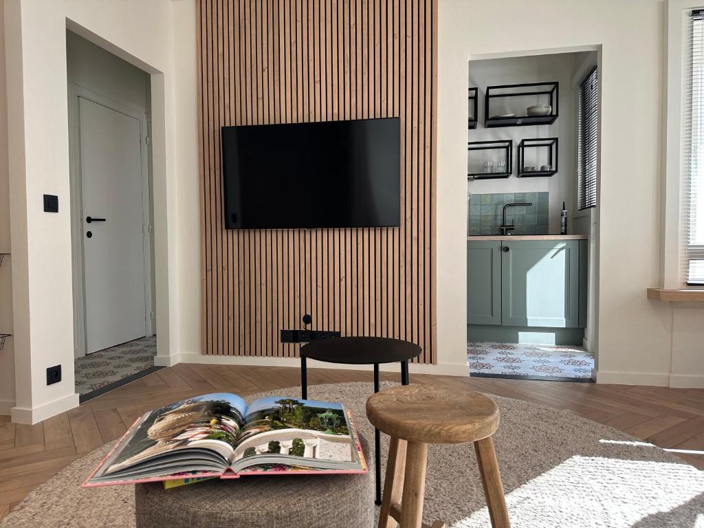 uma sala de estar com uma televisão e uma mesa com um livro em Home away from home em Oostende